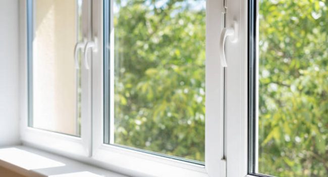 new plastic pvc window with white metal frame installed at modern house, view of blurred green trees. advertising concepts